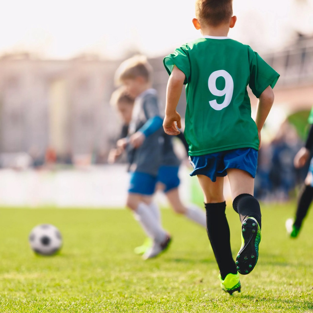 child playing football in green shirt